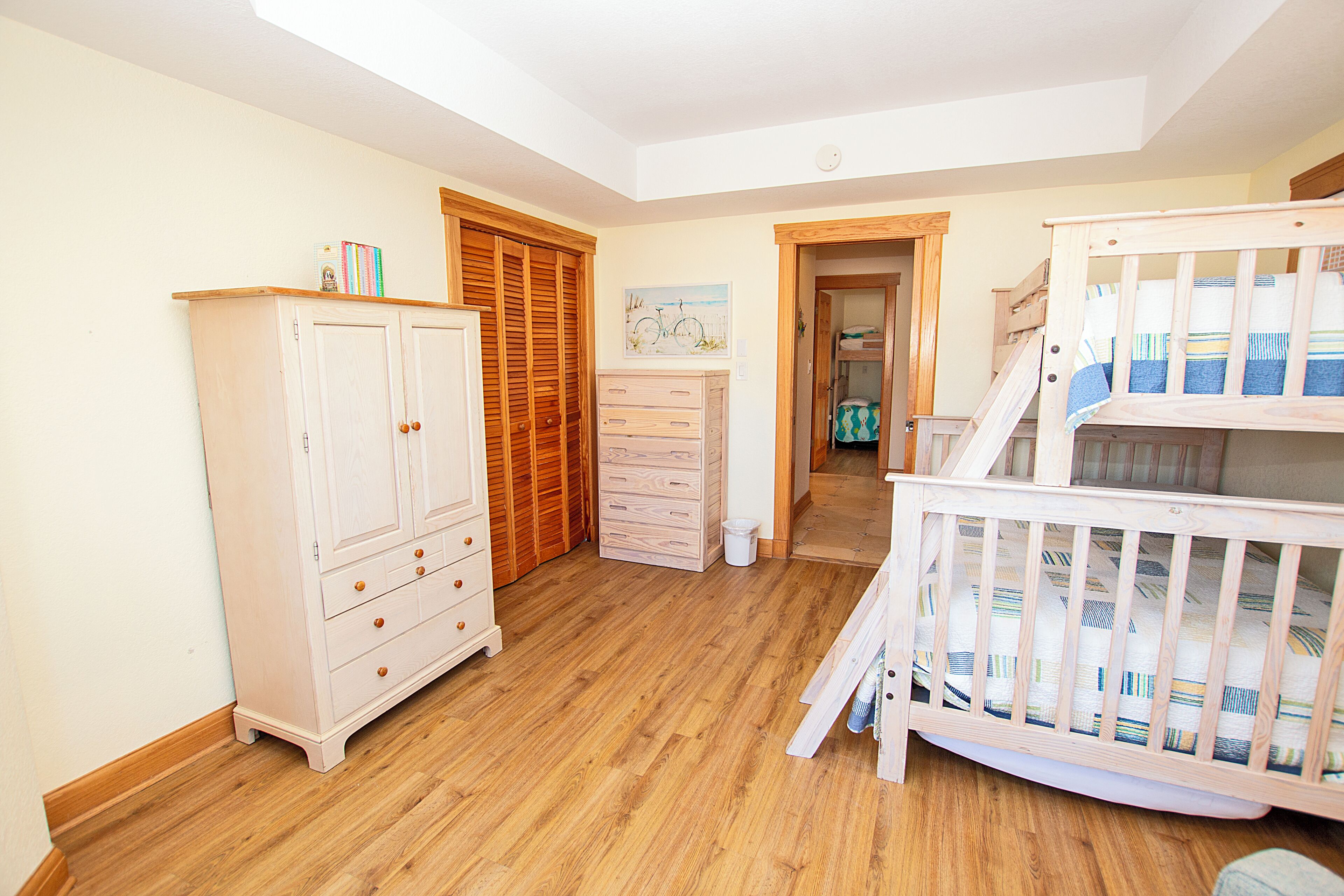 A room with a crib, a wardrobe, and a dresser.