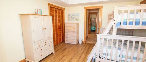 A room with a crib, a wardrobe, and a dresser.