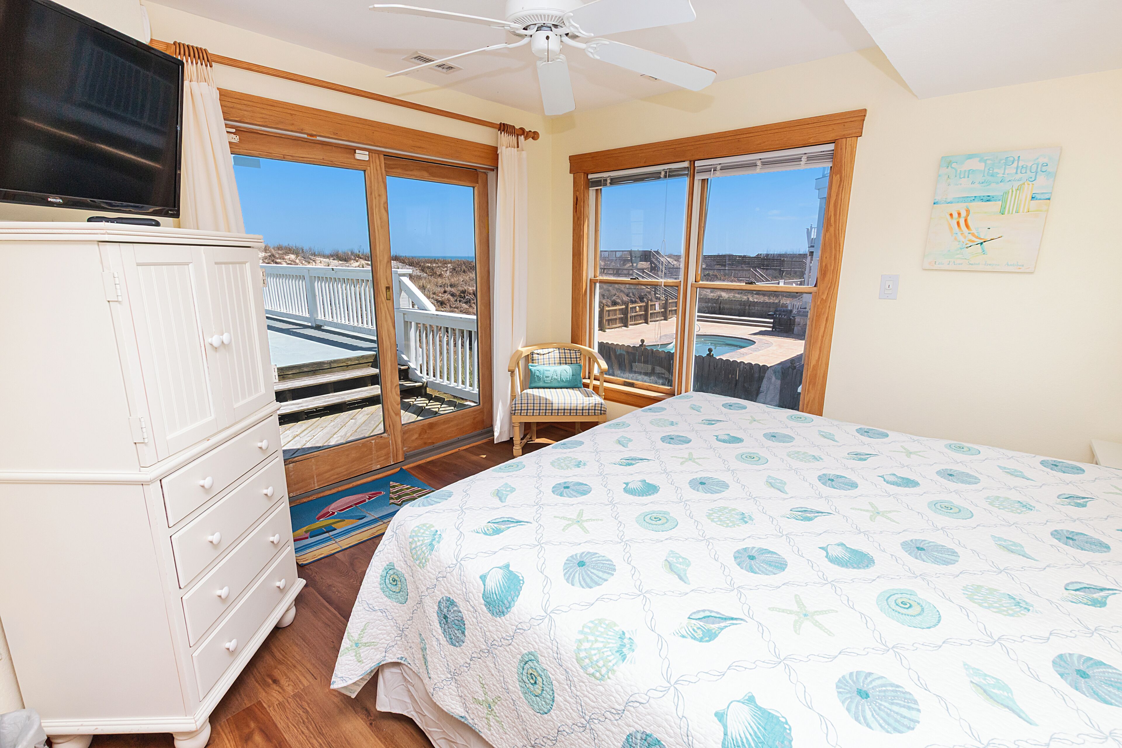 A bedroom with a bed, a dresser, a chair, and a television.