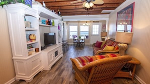 A cozy living room with a television, wicker furniture, and a dining area with a view. - OCEANFRONT, Ocean Views, Sun Deck, KH121, Pirate Queen (Kitty Hawk)