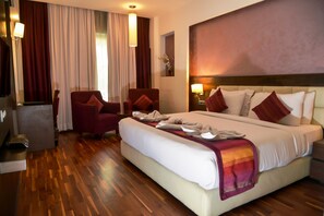 A hotel room with a large bed, two armchairs, a desk, and a TV. - Hotel Almeida (Dera Bassi)