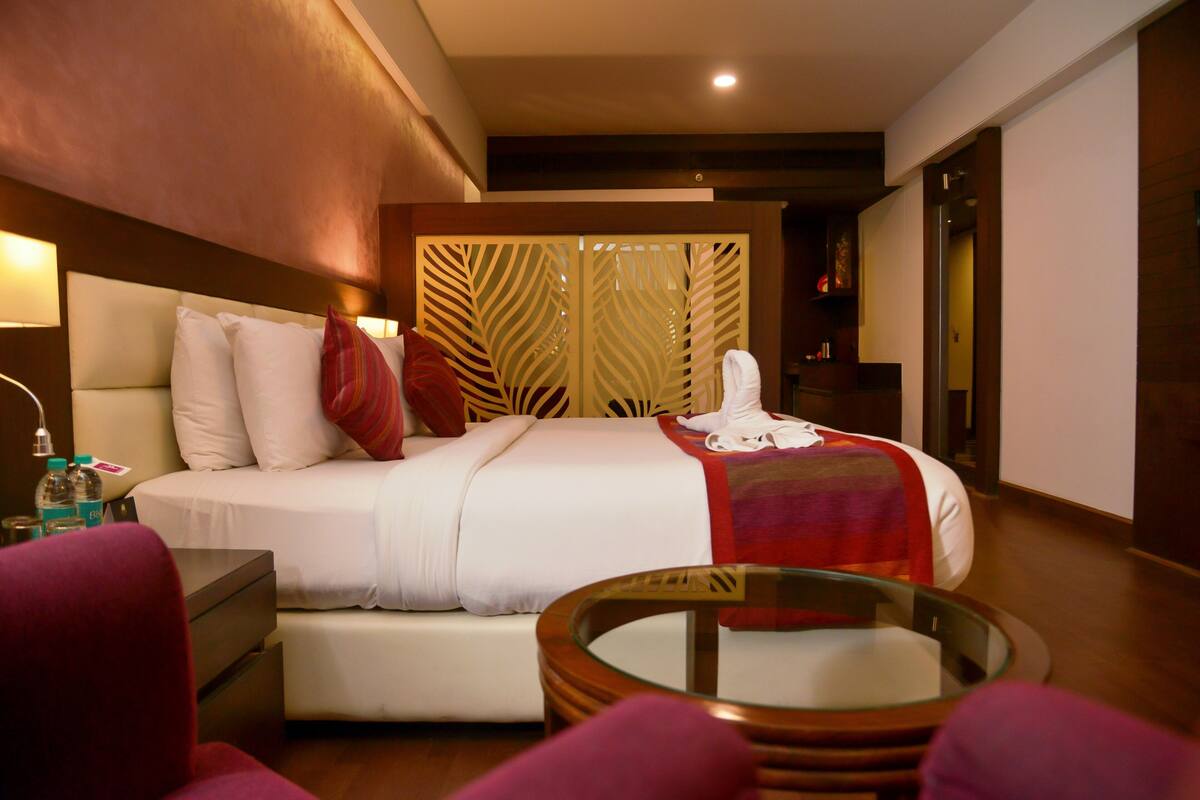 A hotel room with a bed, bedside table, and a glass table with chairs.