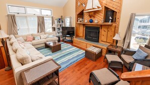 Ein gemütliches Wohnzimmer mit Sofa, Sesseln, Kamin und Fernseher.