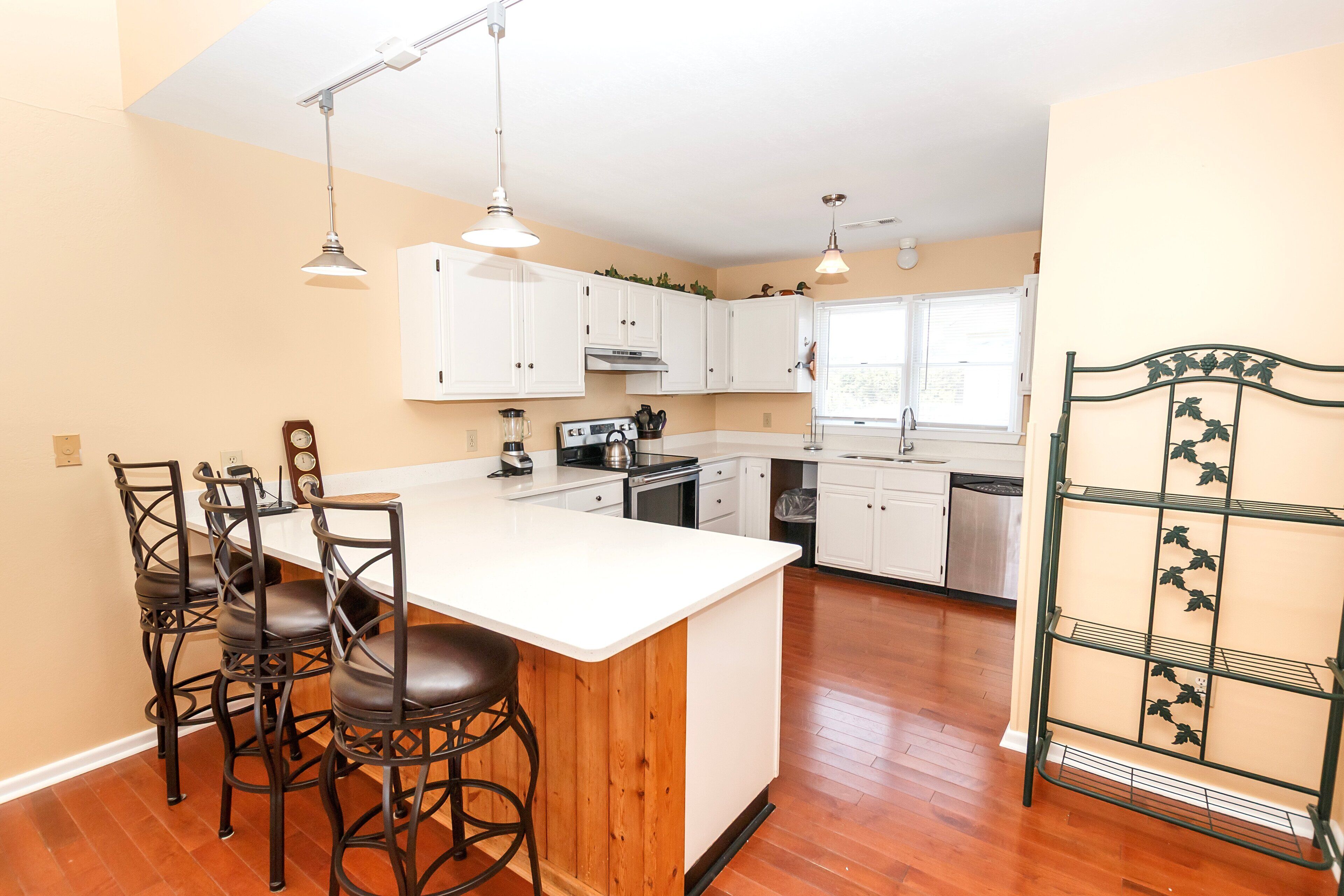 A kitchen with white cabinets, a wooden island, and a black metal chair.