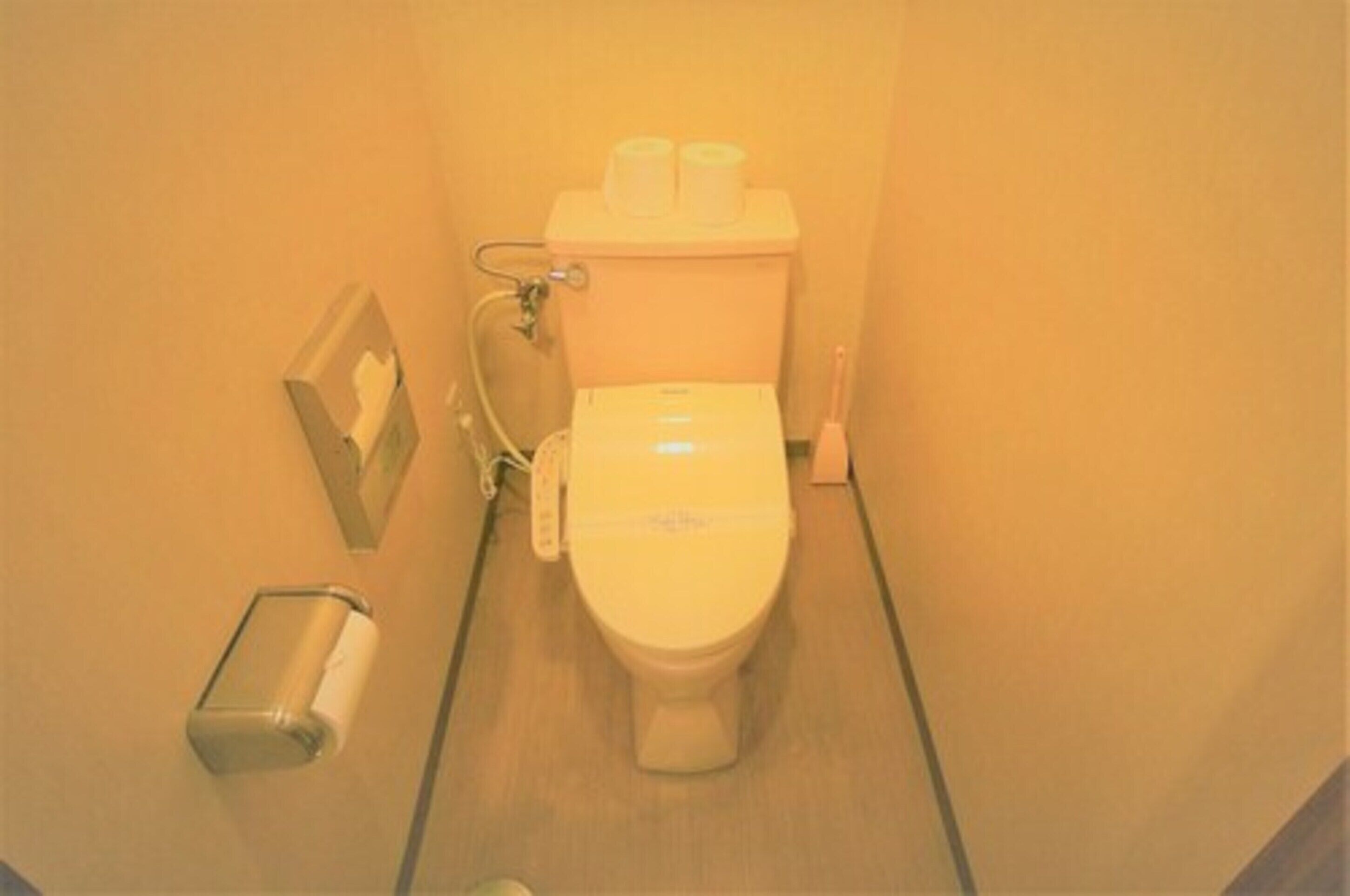 A small, narrow bathroom with a toilet, a hand dryer, and a paper towel dispenser.
