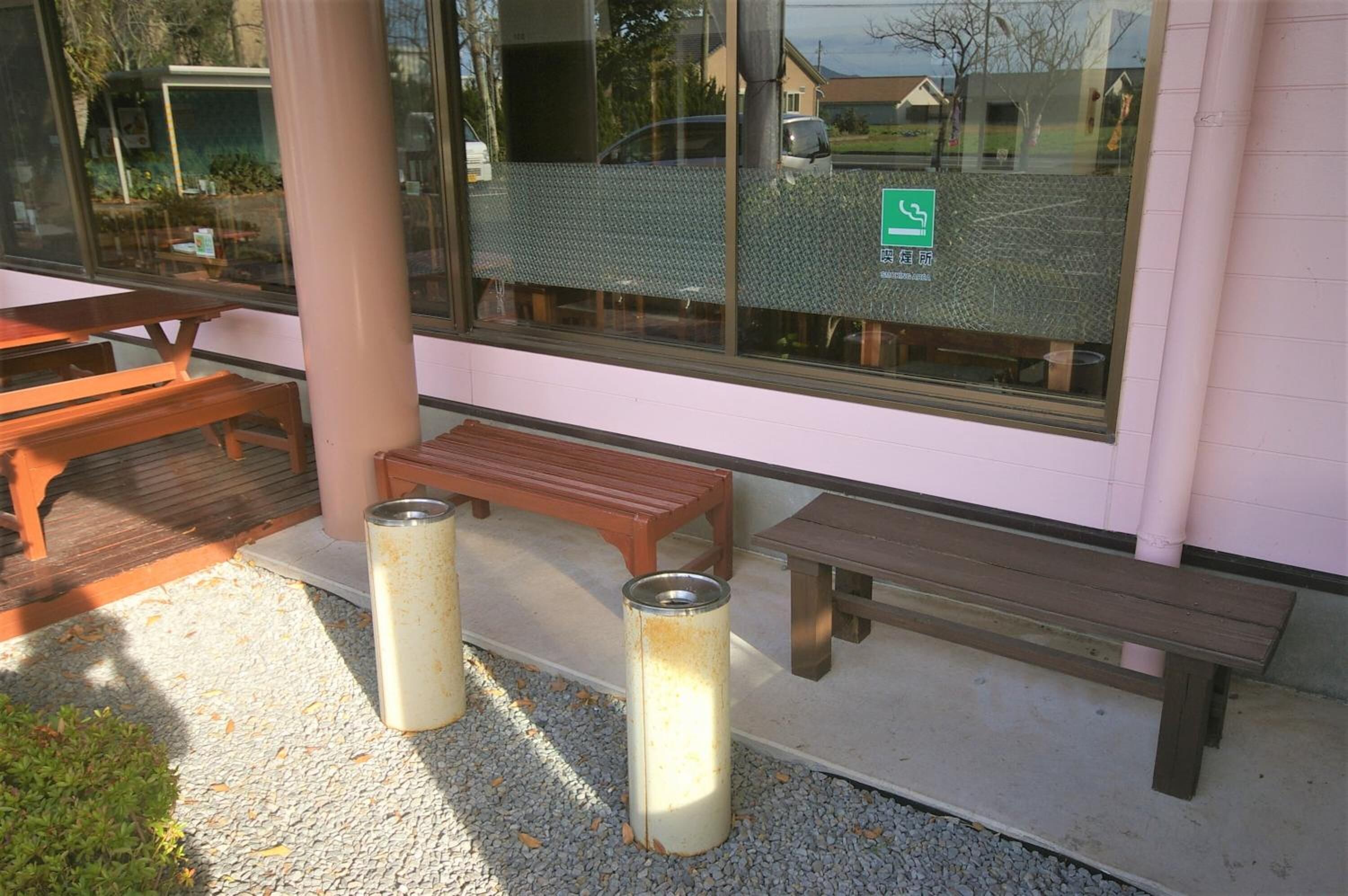 An outdoor seating area with wooden benches and trash cans.