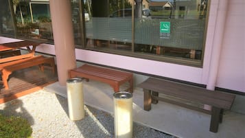 An outdoor seating area with wooden benches and trash cans.