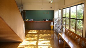 A reception area with a counter, a bench, and a view of greenery through large windows.