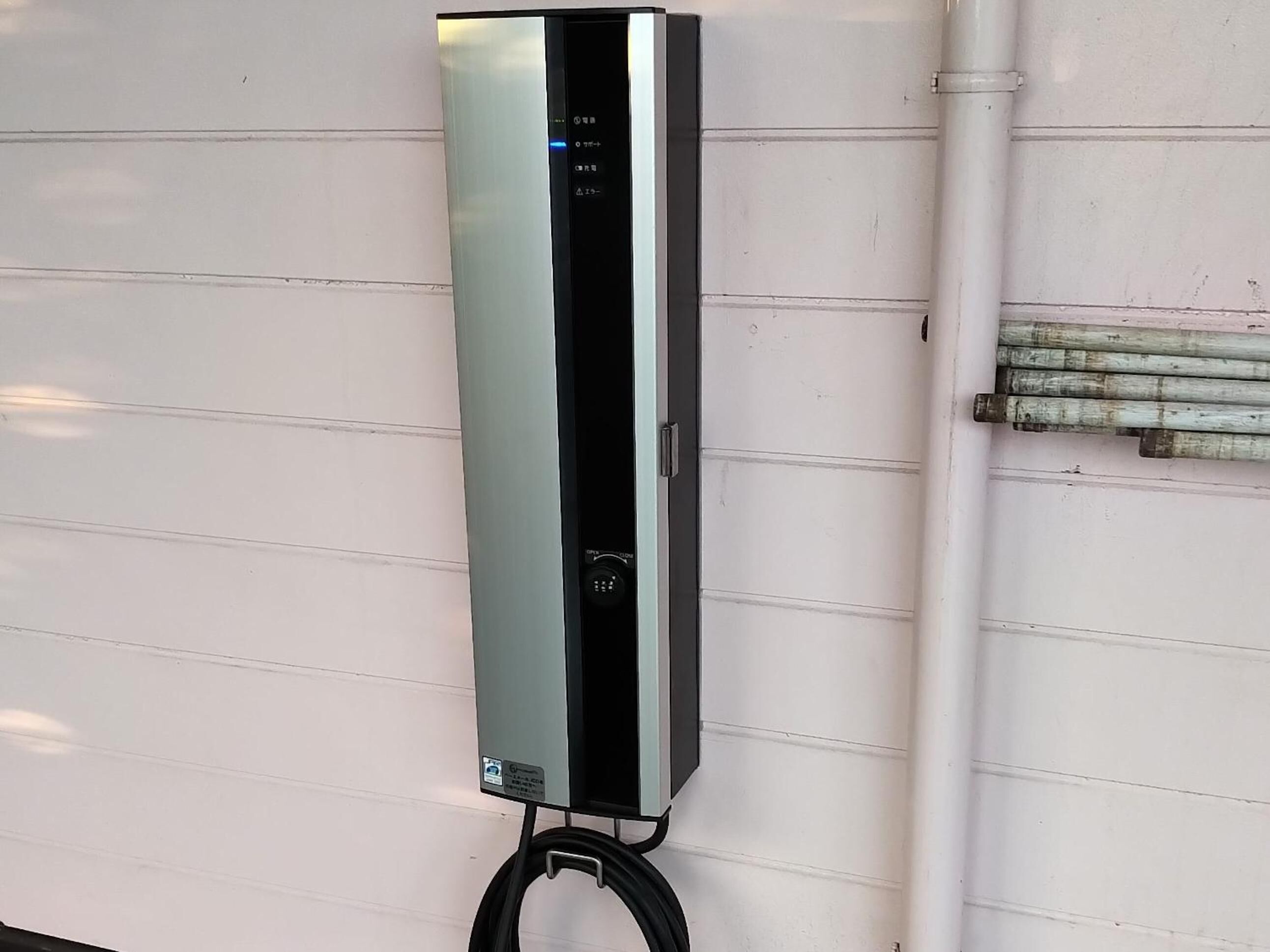Unitat de condicionador d'aire penjada a la paret, amb panell de control i cable d'alimentació.