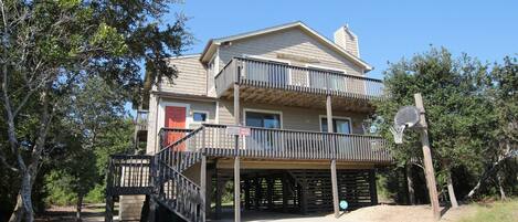 A two-story house with a balcony, a red door, and a basketball hoop.