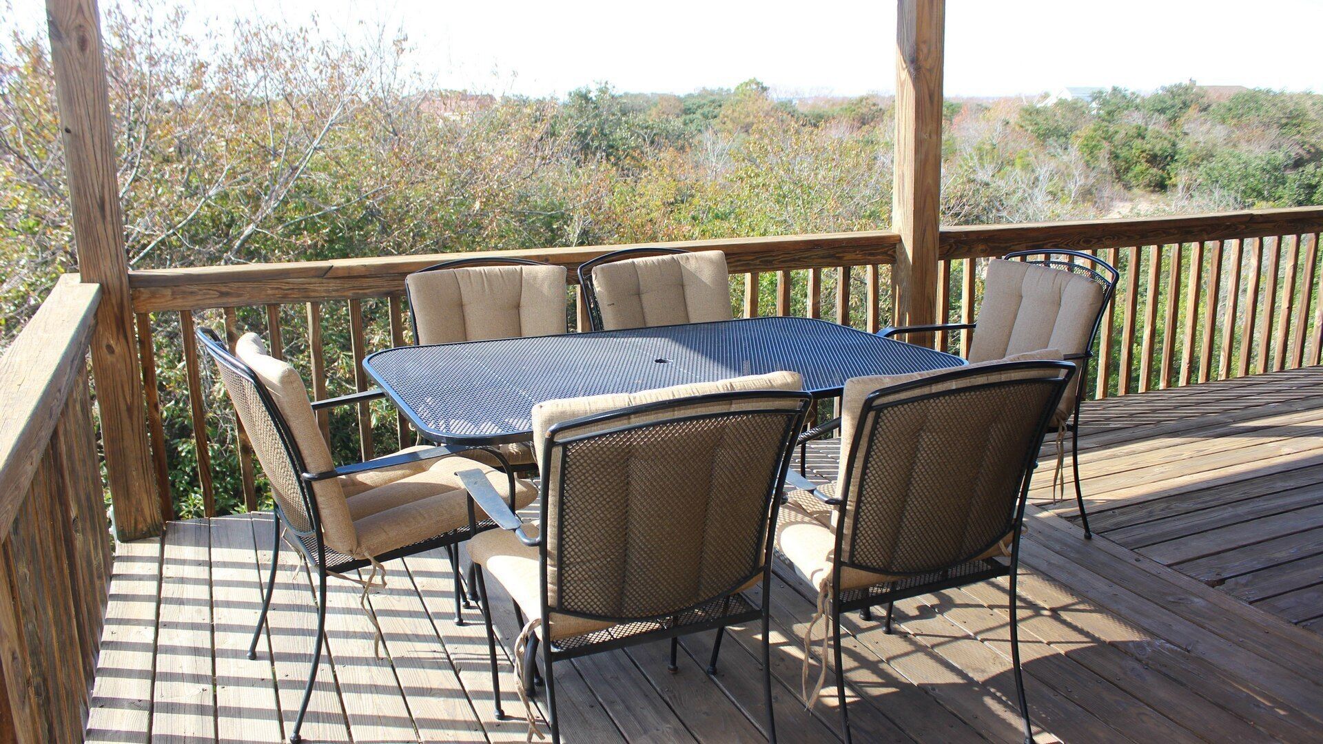A wooden deck with a table and chairs, surrounded by a wooden railing.