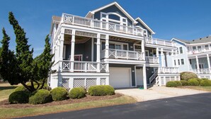 A two-story house with a balcony, a garage, and a well-maintained lawn. - Oceanside, Dogs Welcome, Hot Tub, Close to Shopping, BU13A, Tropical Dreams A (Corolla)