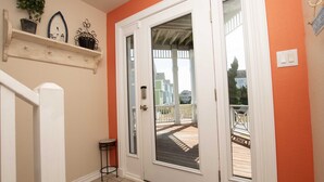 A door leading to a wooden deck with a white door and glass panels, a small potted plant on a shelf, and a white railing outside. - Oceanside, Dogs Welcome, Hot Tub, Close to Shopping, BU13A, Tropical Dreams A (Corolla)