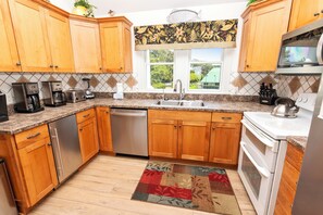 A kitchen with wooden cabinets, a dishwasher, a stove, and a coffee maker. - Soundfront, Dog Friendly, Private Pool, Rec Room, 549, Sunrise Sunset (Corolla)