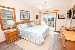 A bedroom with a bed, a nightstand, a dresser, a ceiling fan, and a window with blinds.