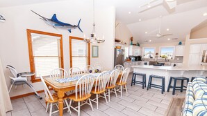Une cuisine spacieuse avec des meubles blancs, un îlot central et un coin repas comprenant une table et des chaises en bois.