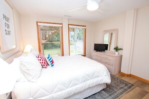 Une chambre à coucher avec un lit, une commode, un téléviseur et un ventilateur de plafond.