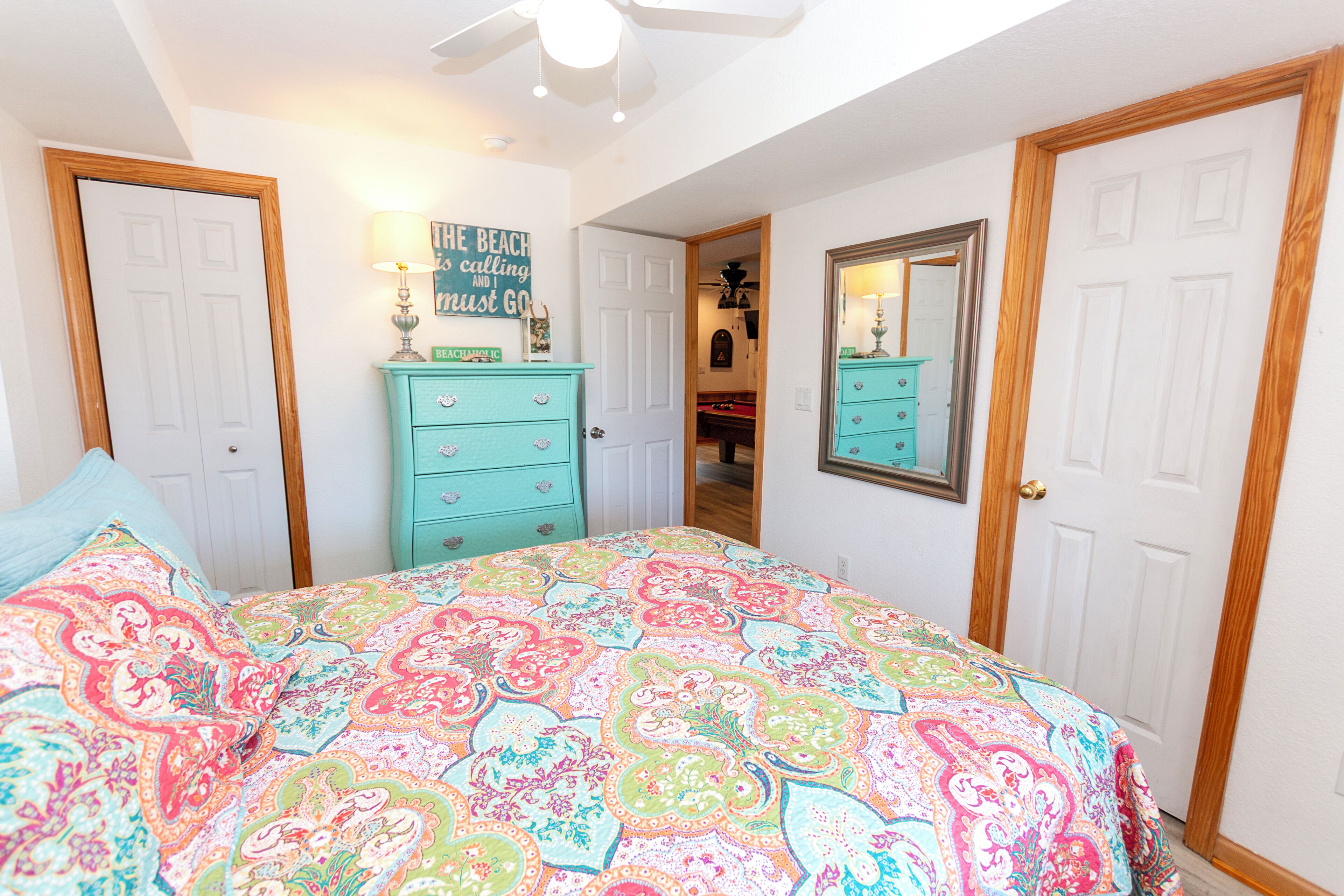 A bedroom with a bed, a dresser, a mirror, and a door.