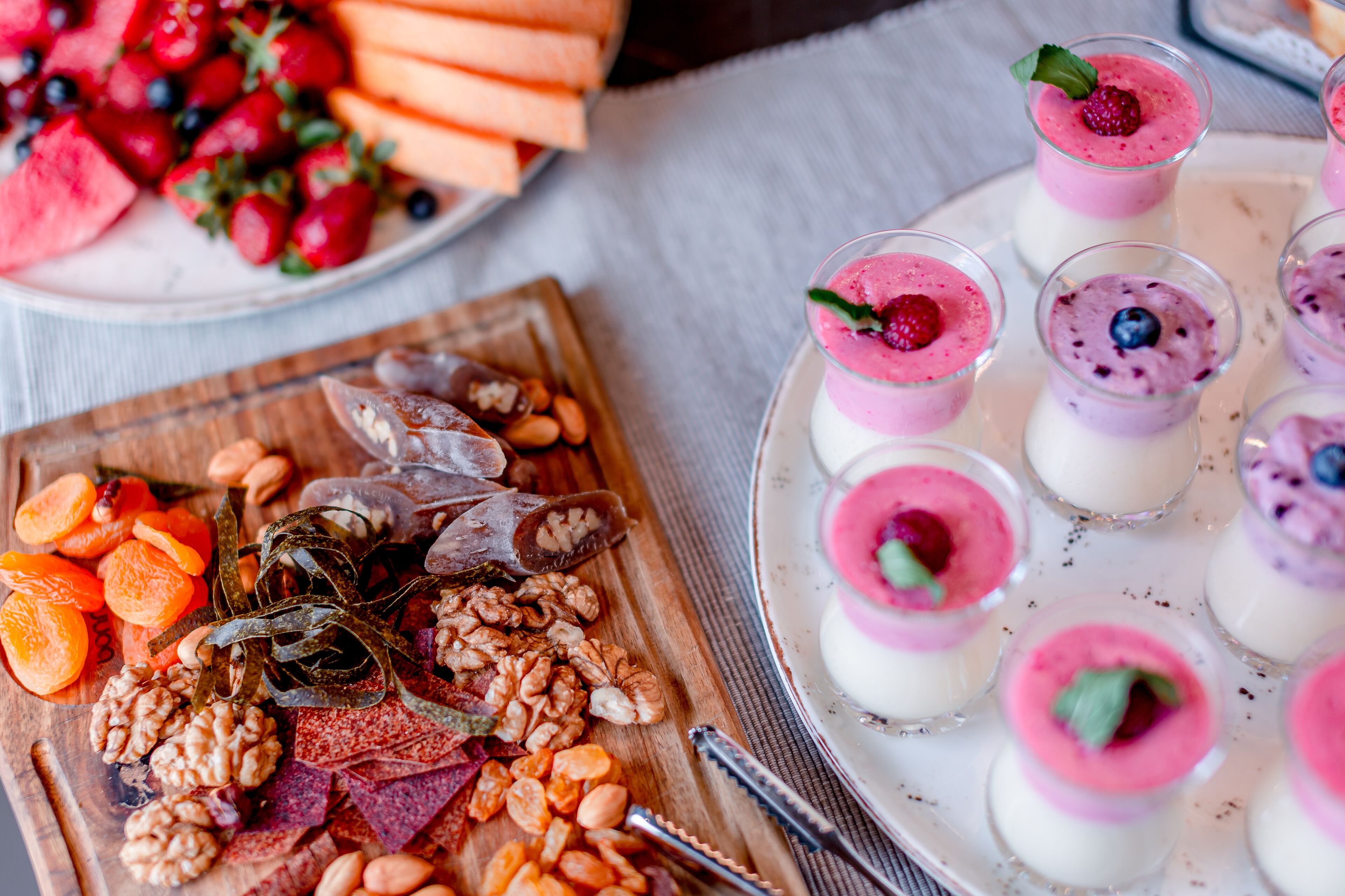 A variety of food items including fruits, nuts, and a plate of layered desserts.