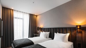 Een hotelkamer met twee bedden, een televisie, een tafeltje en een raam met gordijnen.