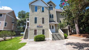 A multi-story residential building with a front entrance, a small porch, and a staircase leading to the entrance. - Soundfront, Private Pool, Hot Tub, Sound Views, Community Amenities, 345, Carolina Sunset (Corolla)