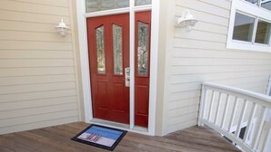 A red door with glass panels, a white railing, and a wooden deck. - Soundside, Community Amenities, Sun Decks, 327, Footprints by the Sound (Corolla)