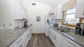 A compact kitchen with white cabinets, granite countertops, a dishwasher, and a window with a view. - Oceanside, Private Pool, Sun Decks, 660 ft to beach access! -WW951, Momma's Happy, Daddys Broke (Corolla)