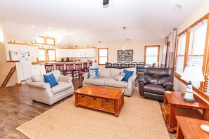A spacious living area with a kitchen, a dining table, and a leather armchair.