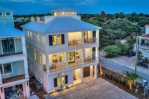Un edificio residencial de varios pisos con balcones, ventanas amplias y un camino de acceso.