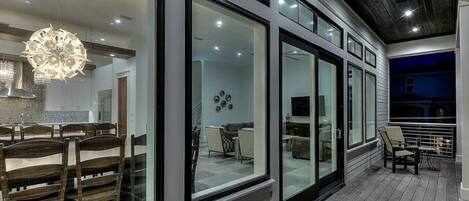 A modern interior with large glass windows, a dining area with wooden chairs, and a ceiling with recessed lighting.