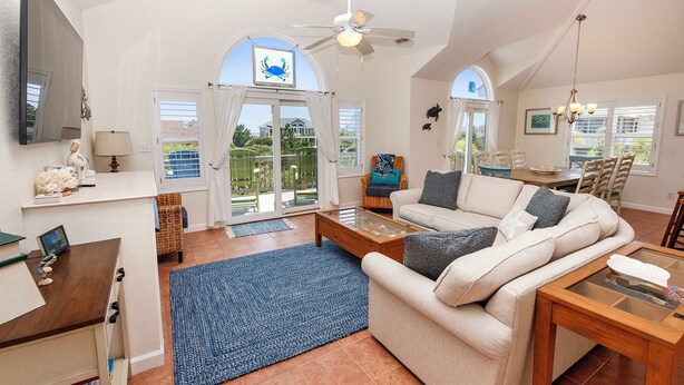 A spacious living room with a sofa, coffee table, and a TV mounted on the wall. - Oceanside, Priv Pool, Hot Tub, OS Shuffleboard, Rec Rm, WW1039, Island So Remote (Corolla)