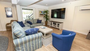 A living room with a striped sofa set, a blue armchair, a flat-screen TV, and a potted plant. - Oceanside, Priv Pool, Hot Tub, OS Shuffleboard, Rec Rm, WW1039, Island So Remote (Corolla)