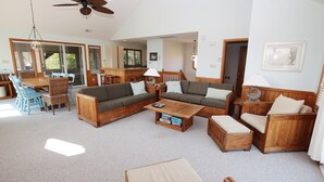 A spacious living room with a large wooden sofa set, a coffee table, and a dining area with a wooden table and chairs. - Oceanside, Private Pool, Hot Tub, Screened Porch, 650 ft to Beach Access, WW1021, Zip-A-Dee-Dune-Dah (Corolla)