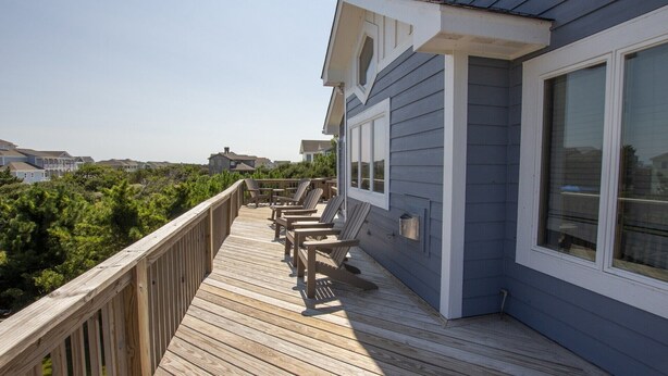 A wooden deck with chairs, a railing, and a house with large windows. - Oceanside, Private Pool, Hot Tub, Screened Porch, 650 ft to Beach Access, WW1021, Zip-A-Dee-Dune-Dah (Corolla)