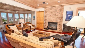 A spacious living room with a large sofa, a fireplace, and a view of the outside. - Oceanside, Screened Porch, 100 ft to Beach Access, SA180, Siren Song (Duck)