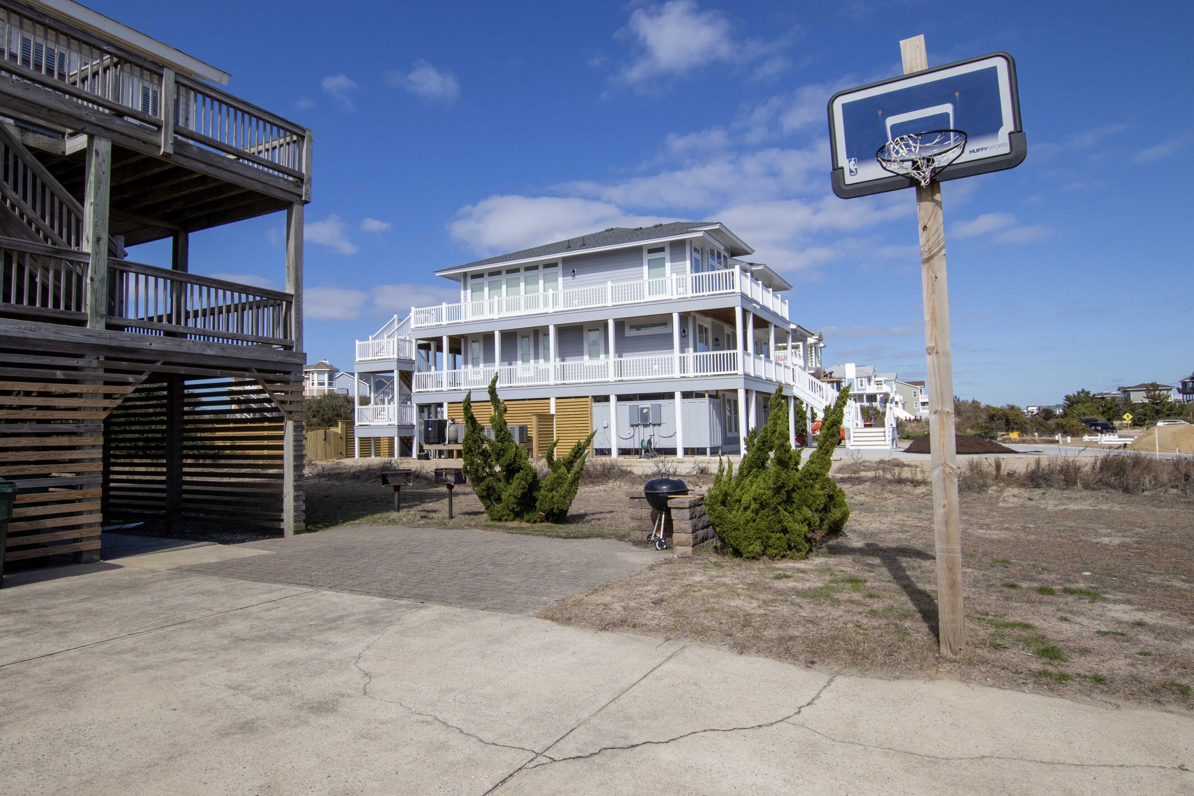 Una propiedad frente a la playa con un edificio de varios niveles, una cancha de baloncesto y una zona de barbacoa.