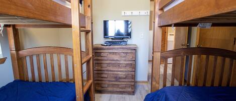 Habitación con literas y un televisor sobre un tocador.