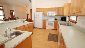 A modern kitchen with wooden cabinets, a stainless steel sink, a microwave, a refrigerator, and a stove. - Oceanside, 7 BRs, ELEVATOR, Private Pool, Hot Tub, OH3, Aurora (Corolla)