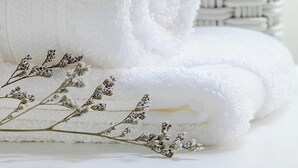 Una toalla blanca enrollada, una cesta tejida y flores de lavanda secas.