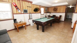 Una sala con piscina, mesa de billar, sillas y una máquina de café.