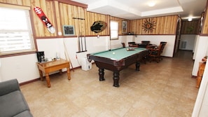 A pool room with a pool table, chairs, and a coffee machine.
