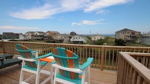 Une terrasse en bois avec deux chaises Adirondack aux couleurs vives, donnant sur la plage.
