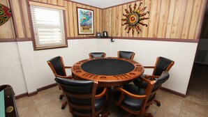 A conference room with a round wooden table, six black leather chairs, wooden paneled walls, and a decorative sun on the wall. - Oceanside, 5 BRs, Hot Tub, Rec Room, Close to Shopping, KH221, Shoebies Hangout (Kitty Hawk)