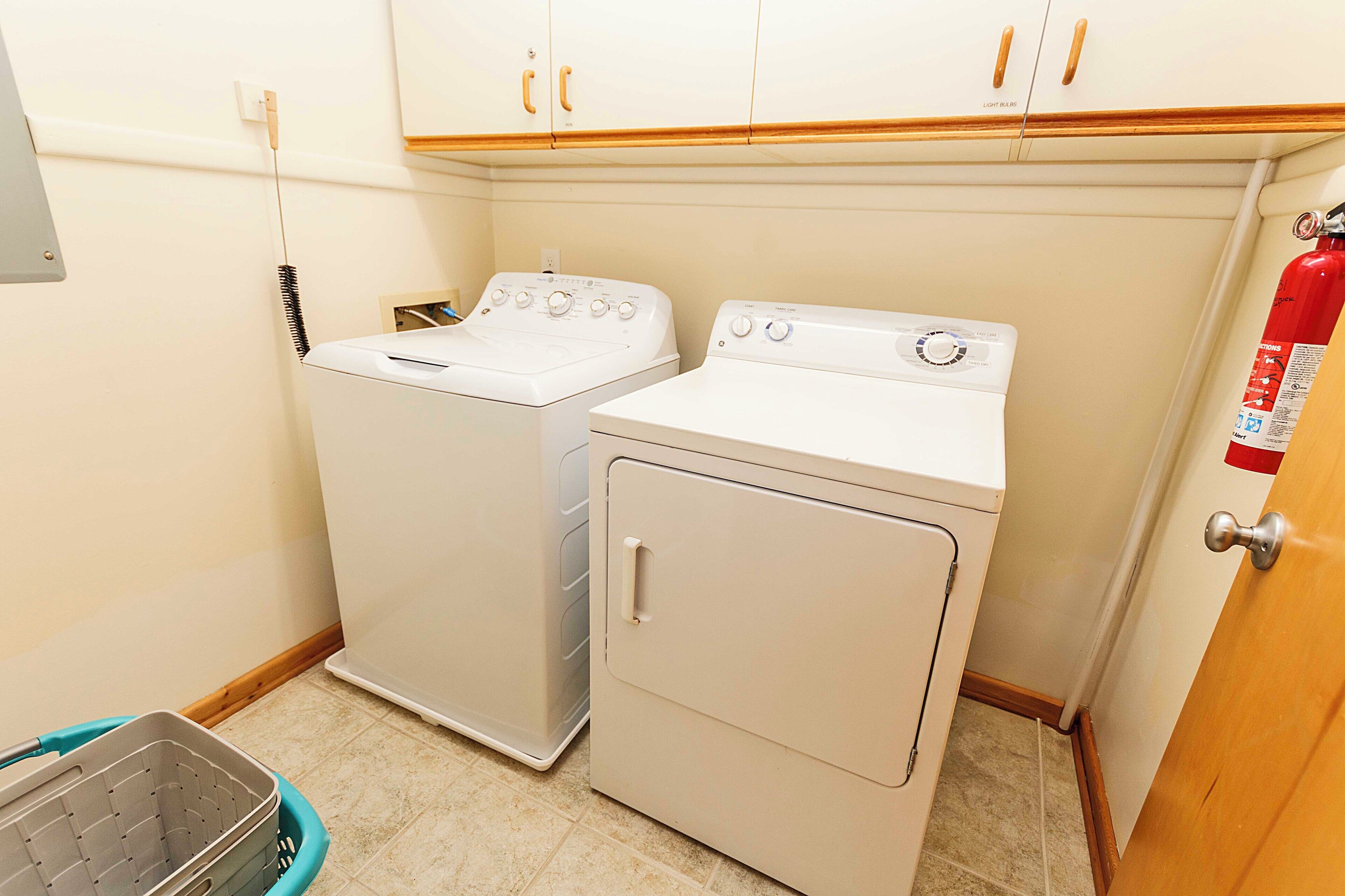 A laundry area with two washing machines and a fire extinguisher.