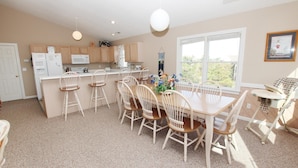 A kitchen with a dining area, white cabinets, a microwave, and a window with a view.