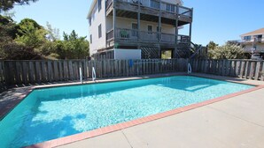 A rectangular swimming pool with a wooden deck and a wooden fence surrounding it.