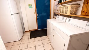 A laundry room with a washing machine, dryer, and a blue door.