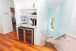 Una cocina con cafetera espresso integrada, refrigerador y ventana con vista a follaje.