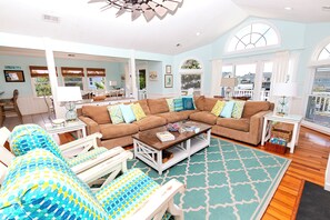 A spacious living room with a large sectional sofa, a coffee table, and a patterned rug. - Oceanside, Private Pool, Hot Tub, Close to beach access, 224, Its All Good (Corolla)