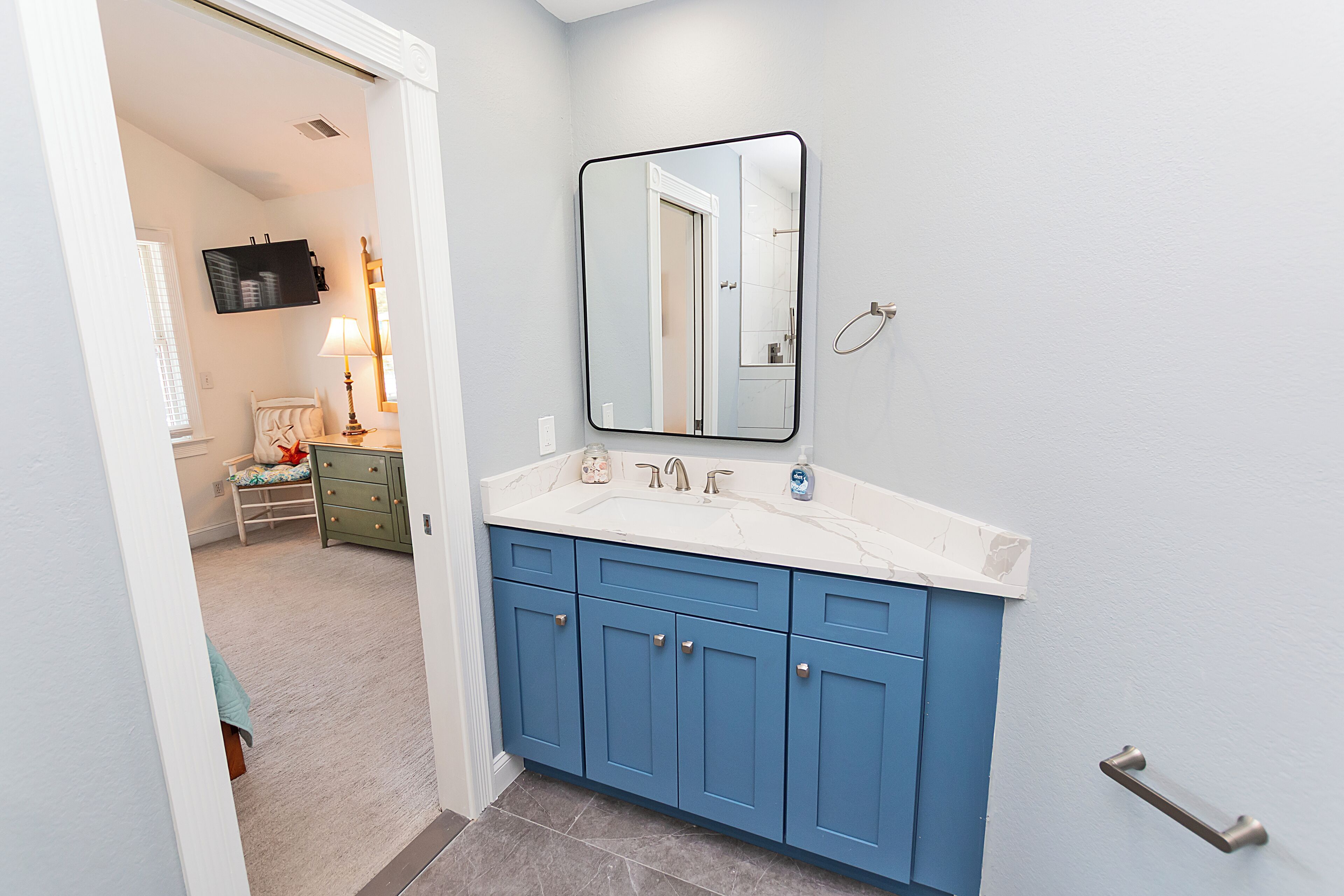A bathroom with a white sink, blue cabinets, a mirror, and a towel rack.